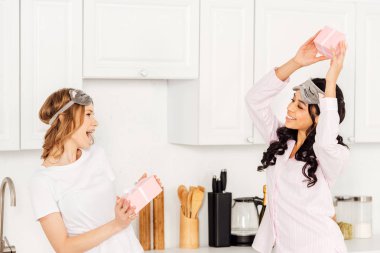 uyku maskesi ve hediye kutuları mutfakta ile pijama giyen güzel mutlu çok kültürlü kız