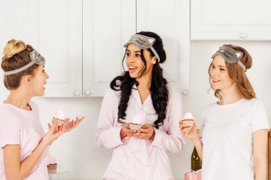 çok ırklı kızlarda güzel kek tutarak ve pijama partisi sırasında konuşurken uyku maskeleri