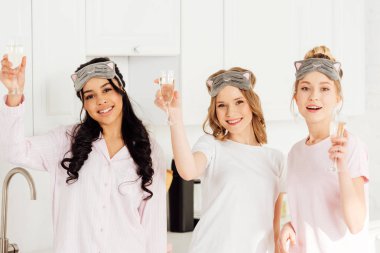 uyku güzel çok kültürlü kızlar maskeleri şampanyalı kutlama ve pijama partisi sırasında kameraya bakıyor