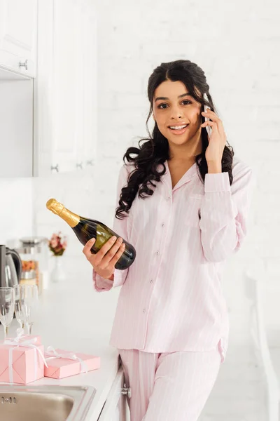 Красивая Улыбающаяся Африканская Американка Держит Бутылку Шампанского Разговаривая Смартфону — стоковое фото