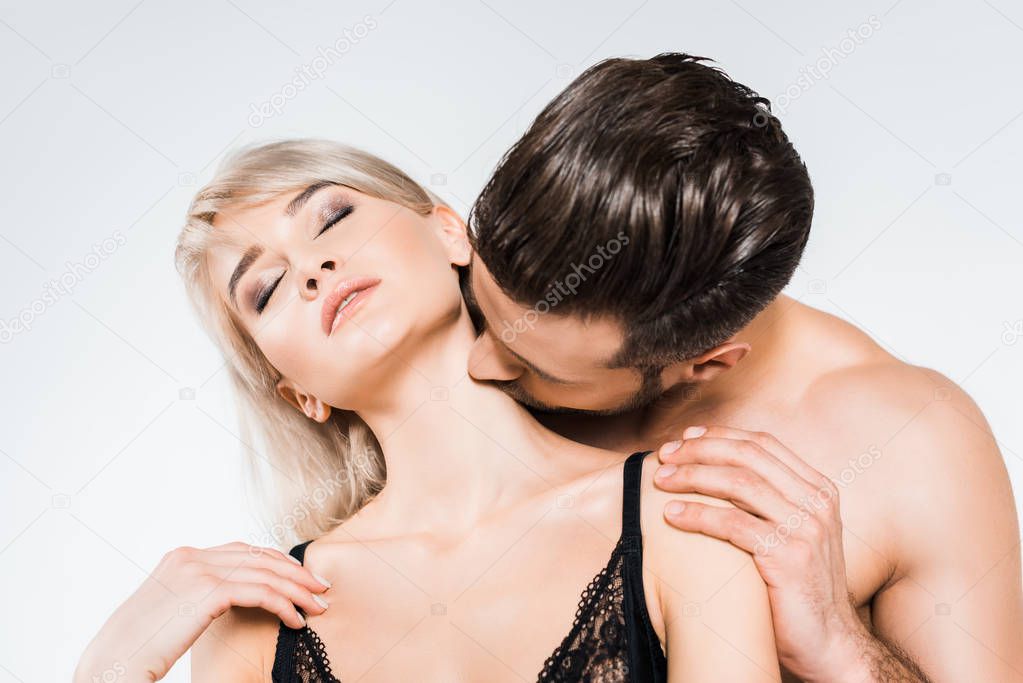 young man kissing neck of tender girlfriend isolated on grey 