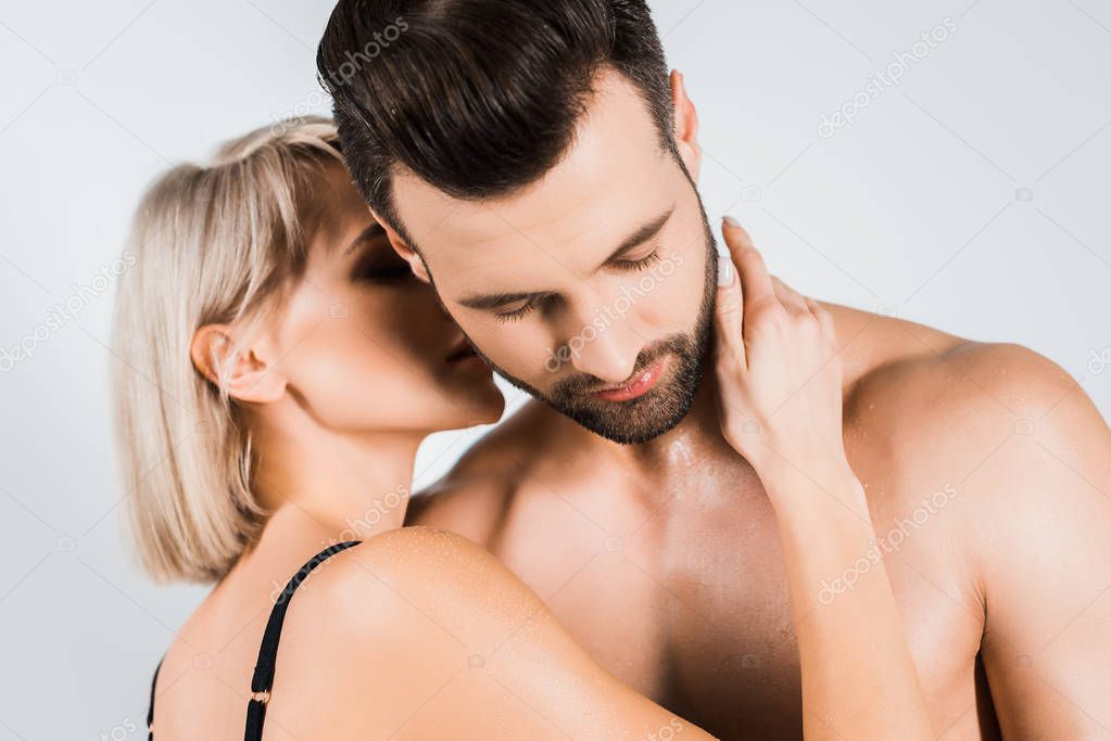 beautiful girl kissing neck of boyfriend isolated on grey 