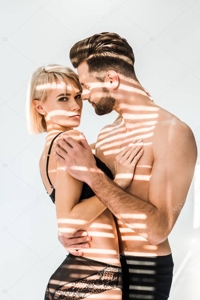 seductive young couple embracing isolated on grey with shadows 