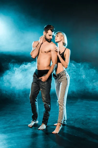 上半身裸の男と官能的な女の子のジーンズで一緒にポーズをとって青煙のような背景 — ストック写真