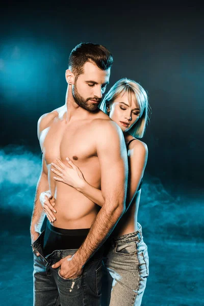 Donna Sensuale Abbracciando Bello Uomo Senza Camicia Sfondo Blu Fumoso — Foto Stock