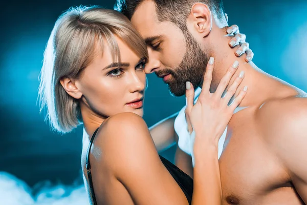 şehvetli kız kucaklayan gömleksiz erkek mavi dumanlı arka plan üzerinde