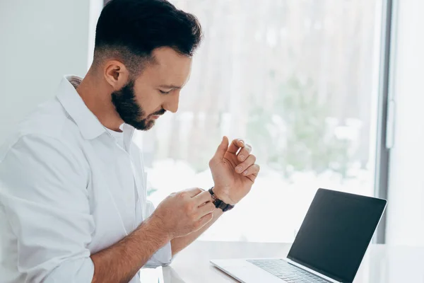 Brunette Man Met Laptop Zetten Polshorloge — Stockfoto