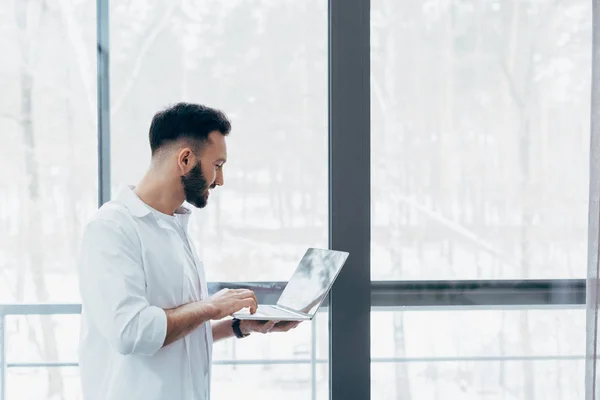 Bearded Man White Shirt Standing Window Holding Laptop — Stock Photo, Image