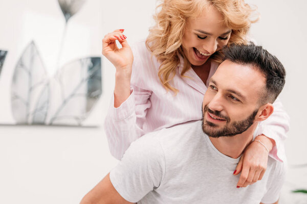 Blissful romantic couple smiling while embracing at home