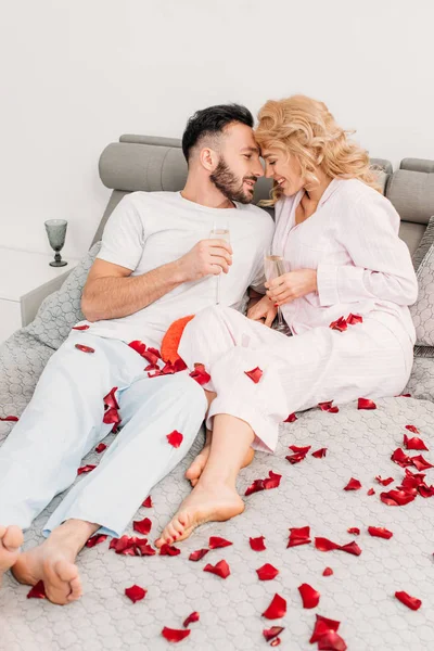 Sorrindo Casal Bebendo Champange Enquanto Deitado Cama Pétalas Rosa — Fotografia de Stock