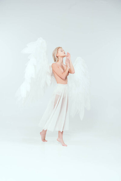 beautiful tender woman with angel wings gesturing with hands and posing isolated on white