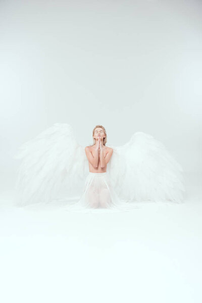 beautiful woman with angel wings praying isolated on white with copy space