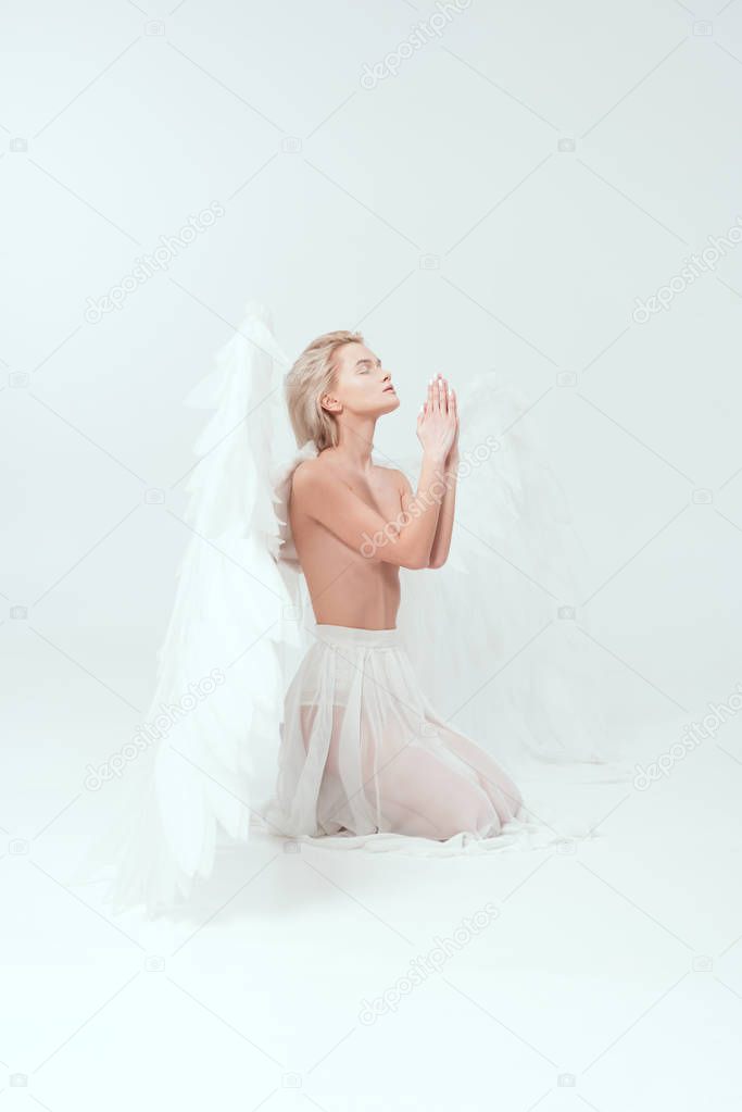 beautiful woman with angel wings praying isolated on white