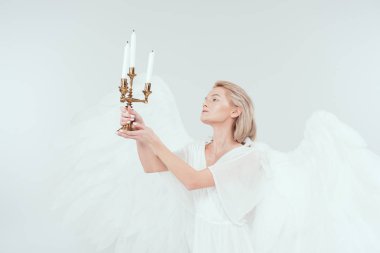 Pyres üzerinde beyaz izole mum tutan kanatlı melek kostüm güzel kadın