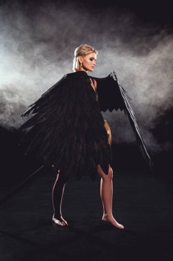 beautiful woman with black angel wings and sword posing on black background clipart