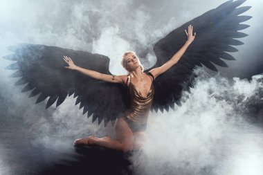 kara melek kanatları ve oturma ve karanlık dumanlı arka plan üzerinde poz uzanmış eller güzel seksi kadın