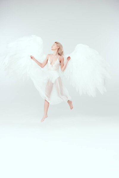 beautiful woman in angel costume with wings jumping isolated on white with copy space