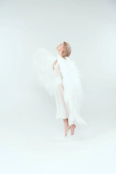 美丽的女人在天使服装与翅膀跳跃被隔绝的在白色 — 图库照片