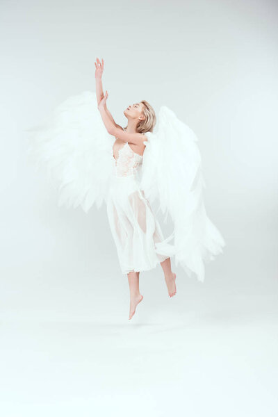 beautiful woman in angel costume with wings jumping on white background
