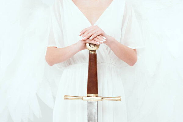 cropped view of woman with angel wings holding sword isolated on white