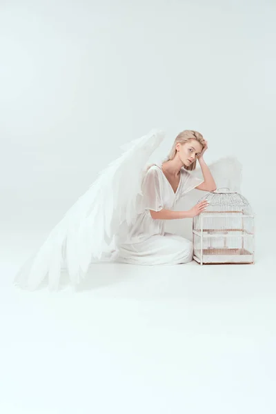 カメラ目線と白で隔離鳥篭とポーズの翼を持つ天使衣装で美しい女性 — ストック写真