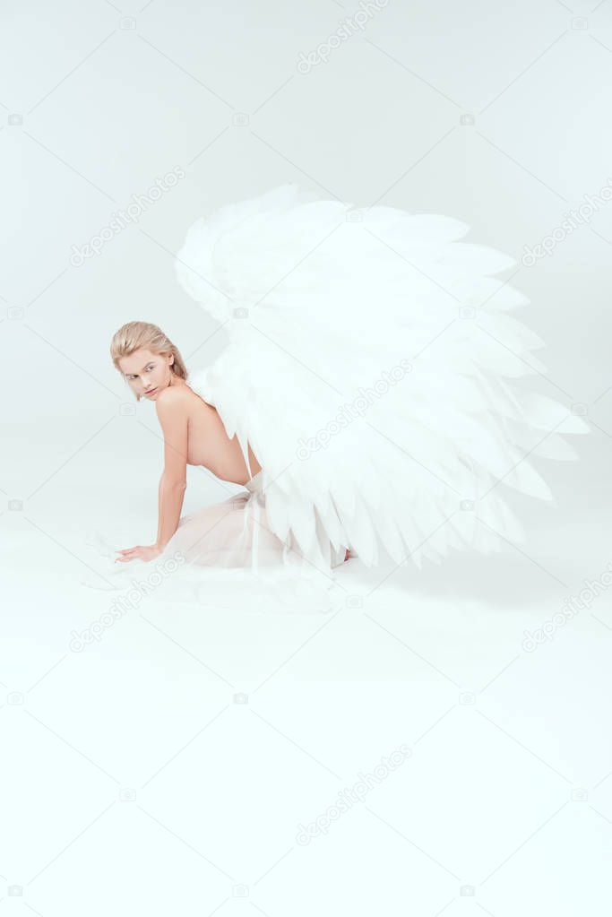 beautiful half naked young woman with angel wings posing on white background