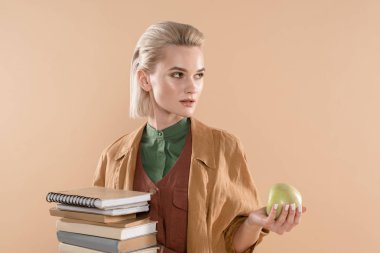çekici kız kitap ve yeşil elma duran Eko giyim üzerinde bej izole holding