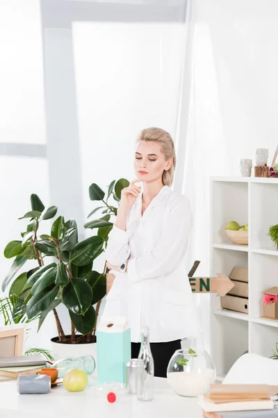 Nachdenkliche Frau Schreibtisch Mit Glasflaschen Dosen Und Papiermilchverpackung Büro Umweltschutzkonzept — Stockfoto