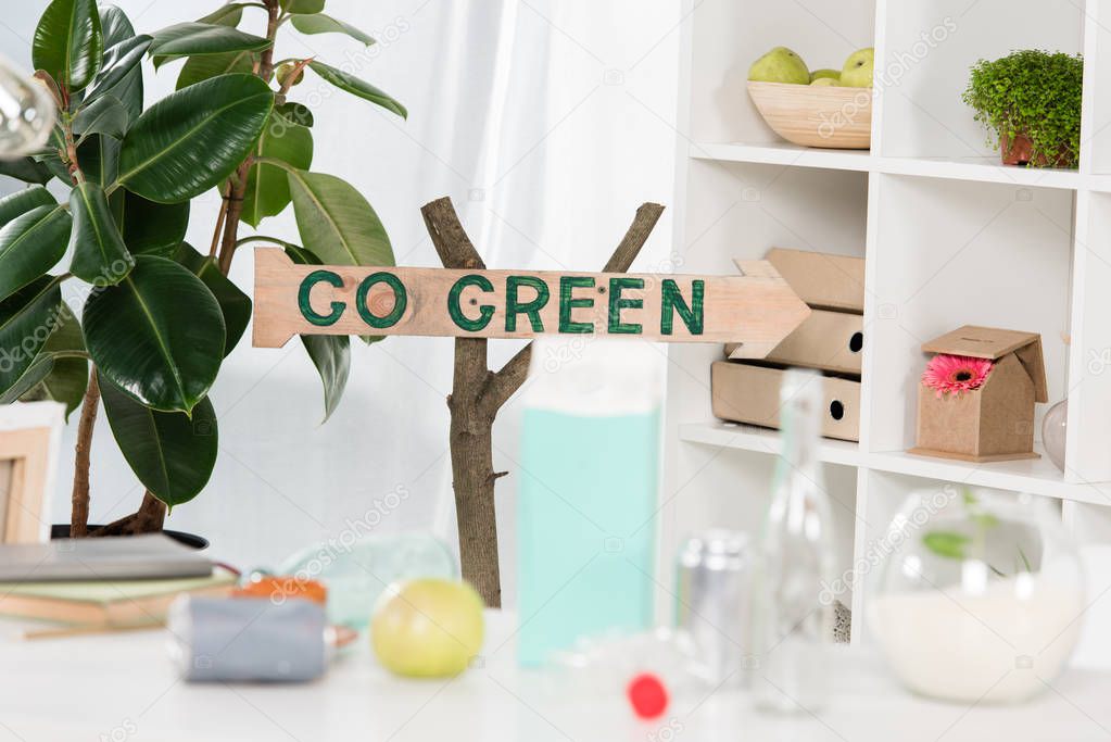 selective focus of wooden sign with go green lettering near workplace in office,  environmental saving concept 