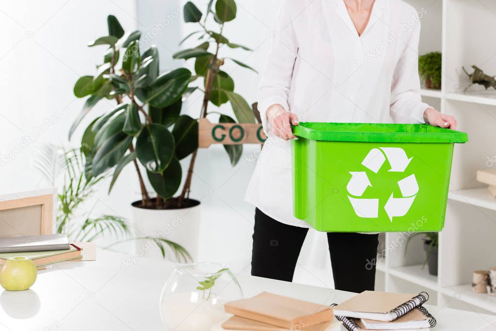 cropped view of woman holding recycling box while standing in office, environmental saving concept 