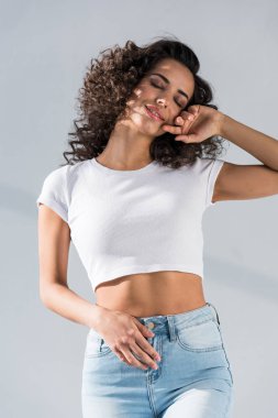 Harika esmer kız kot pantolon kapalı gözler gri arka plan ile poz
