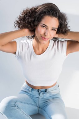 Saçları gri arka plan üzerinde oynarken Jeans çarpıcı esmer kız