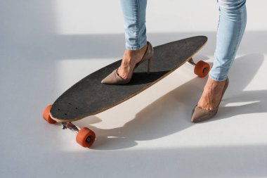 Yüksek topuklu ayakkabılar longboard üzerinde duran kadının kırpılmış görünümü