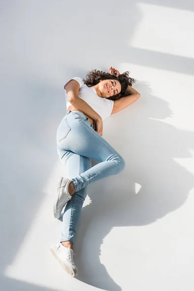 Anmutiges Brünettes Mädchen Jeans Liegt Auf Heller Oberfläche — Stockfoto