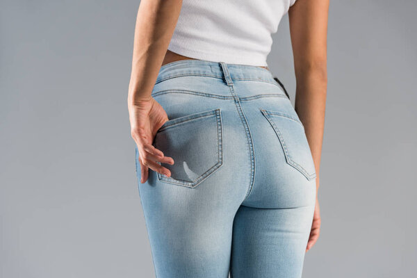 Cropped view of shapely girl in blue jeans isolated on grey