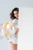 charmante brünette Mädchen mit Luftballons auf grauem Hintergrund