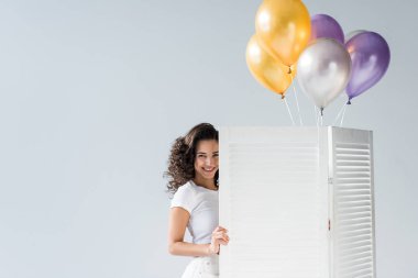 Gri arka plan üzerinde gülümseyen hava Balonlu güzel kıvırcık kız