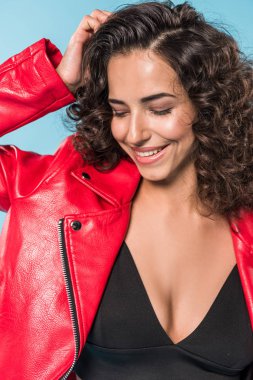 Woman in red leather jacket laughing on blue background