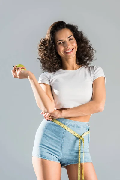 Cheerful Curly Girl Shorts Measuring Tape Holding Green Apple Isolated — Stock Photo, Image