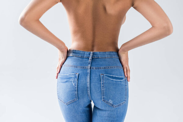 Cropped view of nude sexy woman in jeans on grey background
