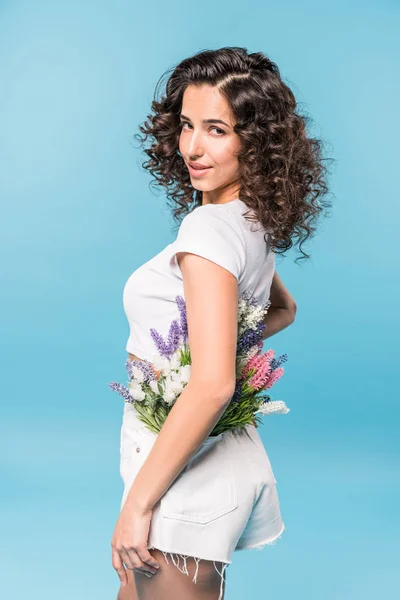 Attractive curly girl holding flower bouquet on blue background