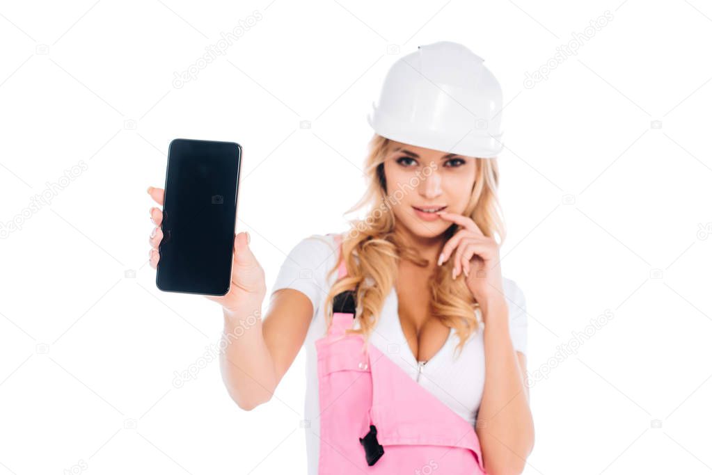 handy woman in pink overalls standing and holding smartphone with blank screen isolated on white
