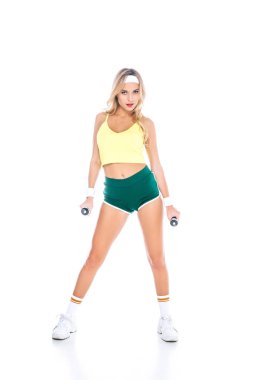 attractive blonde fitness trainer in green shorts and yellow singlet with dumbbells on white background clipart