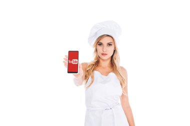 ekranda beyaz izole smartphone youtube uygulaması ile tutarak üniformalı çekici sarışın aşçı kadın