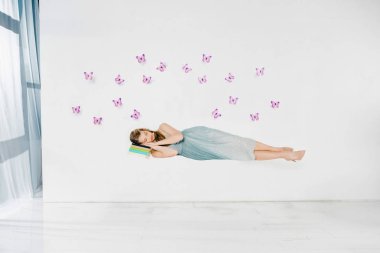  Beyaz arka plan üzerinde havada kitap üstünde mor kelebekler uyumak mavi elbiseli kız