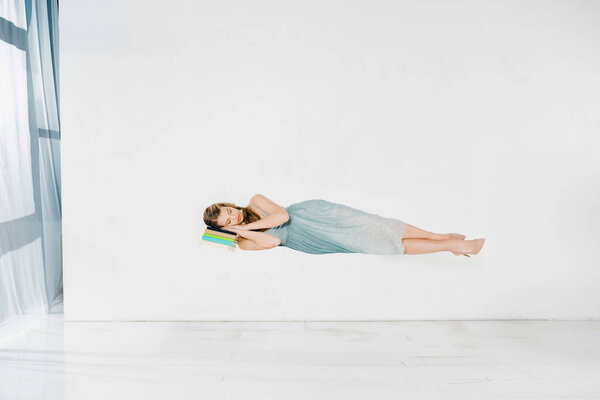  девушка в синем платье спит на книге в воздухе с копировальным пространством
