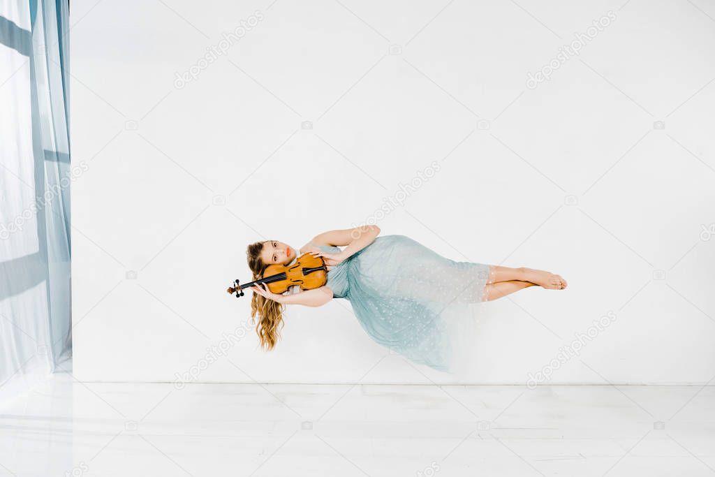  girl in blue dress holding violin in air with copy space