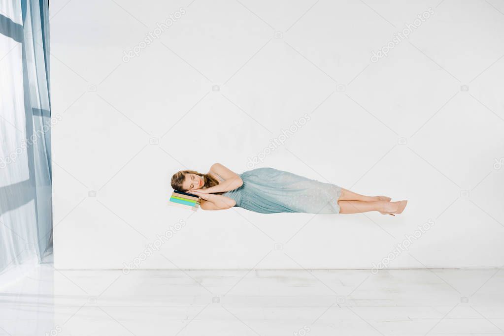  girl in blue dress sleeping on book in air with copy space