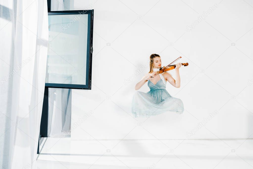 floating girl in blue dess playing violin on white background 