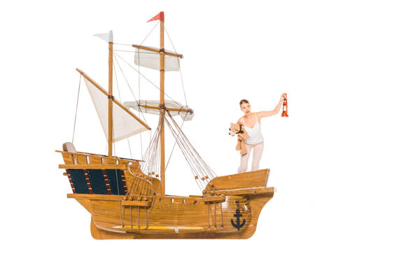 girl in pyjamas holding lantern, teddy bear and standing on floating ship model with copy space
